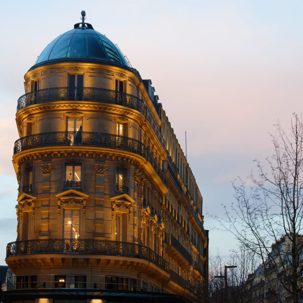 The facade of traditional French house with typical balconies and windows at evening . Paris, France.