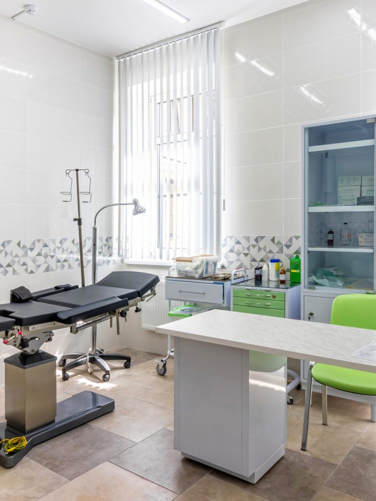 Modern medical office interior with doctor's workplace and examination table.